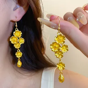 Dettaglio di orecchini pendenti vintage in oro con fiori e un ciondolo a goccia
