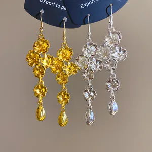 Dettaglio di orecchini vintage a fiori con pendente a goccia nelle varianti oro e argento