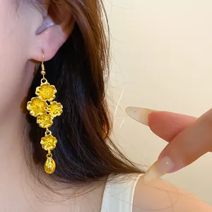Eleganti orecchini pendenti dorati con motivi floreali vintage e un ciondolo a goccia.
