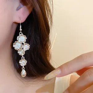 Primo piano di orecchini vintage in argento con fiori e ciondolo a goccia su modella