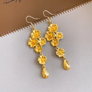 Visuale dettagliata di orecchini pendenti vintage dorati con fiori e ciondoli a goccia.