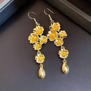Dettaglio ravvicinato di orecchini vintage a fiori dorati con pendenti a goccia d'acqua