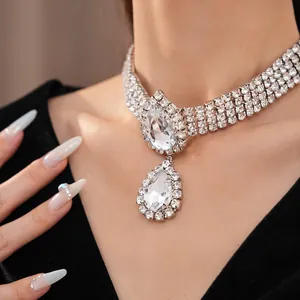 Détail d'un collier avec pendentif goutte d'eau étincelant et chaîne à trois rangs