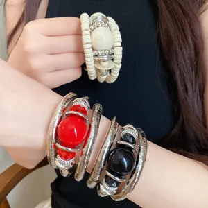 Detail view of retro multi-layer acrylic beaded wrap bracelets on model's arms