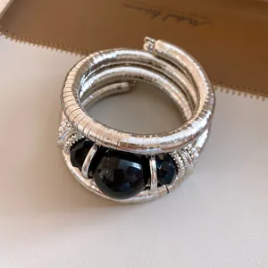 Close-up of a retro silver-tone wrap bracelet with large black acrylic beads