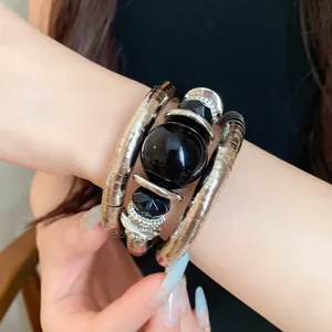 Close-up of a retro multi-layer metal wrap bracelet with elegant black acrylic beads on wrist