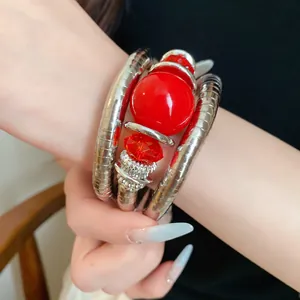 Detailed view of red acrylic beads and silver metallic coil wrap bracelet on wrist