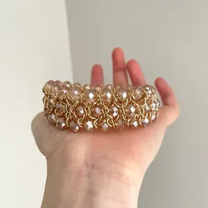 Detalle de una pulsera vintage de cuentas de vidrio ámbar en una mano.