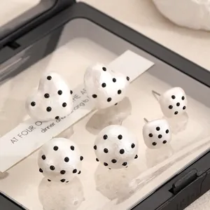 Detailed view of three pairs of black and white polka dot acrylic heart and round ear studs.