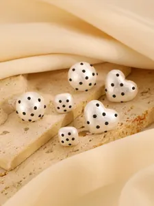 Detailed view of white heart and round acrylic jewelry pieces with black polka dots texture