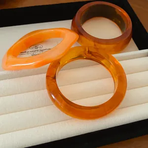 Détail de bracelets en résine ambrée aux formes géométriques sur un présentoir.