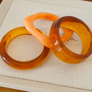 Gros plan de trois bracelets géométriques en résine avec une texture ambre écaille de tortue