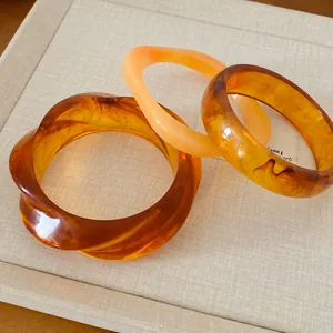 Vue détaillée de bracelets géométriques irréguliers en résine tons ambre et pêche chic