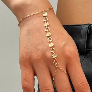 Gros plan d'un bracelet de doigt doré avec des maillons en forme de cœur texturés.