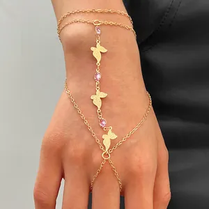Vue détaillée d'un bracelet bague papillon doré mat avec zircon rose sur une main