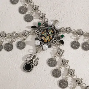 Close-up detail of a vintage ethnic waist chain with silver coins, shells, and pearls.