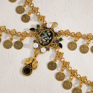 Macro detail of a vintage gold coin waist chain featuring shell and pearl pendants