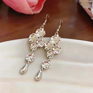 Dettaglio di orecchini a fiore in argento con pendenti a goccia e ganci eleganti.