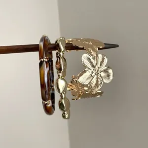 Vue détaillée d'un jonc doré à fleurs ajourées et d'un bracelet en résine écaille de tortue