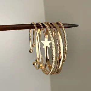 Vue macro détaillée de plusieurs bracelets en métal doré avec un charm étoile et des textures