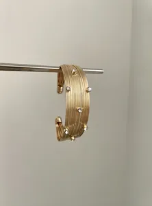 Gros plan sur un bracelet jonc doré à rayures orné de cristaux étincelants