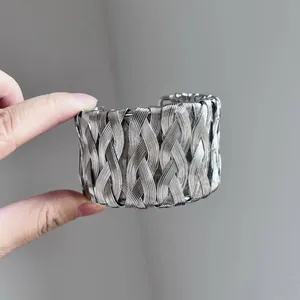Vue détaillée d'un bracelet manchette large argenté au design en fil de métal tressé