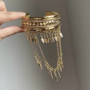 Vue détaillée d'un bracelet manchette doré avec des chaînes à pampilles en feuille