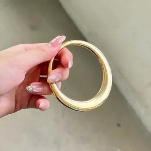 Primer plano de un elegante brazalete vintage de acrílico dorado sostenido en la mano hoy
