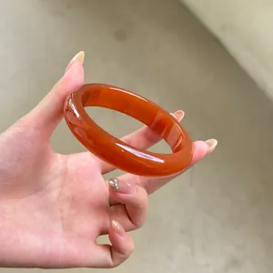 Primer plano de un elegante brazalete vintage de acrílico ámbar sostenido por la mano.