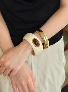 Primer plano de brazalete vintage de acrílico con piedra roja y manguito dorado