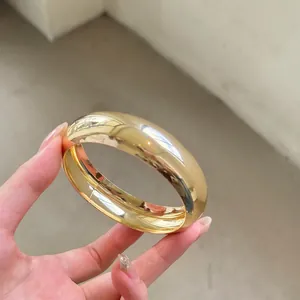 Detalle de un brazalete ancho de acrílico dorado con un acabado metálico de alto brillo