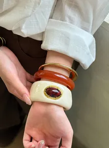 Primer plano de elegantes brazaletes de acrílico vintage con detalles de joyas en la muñeca