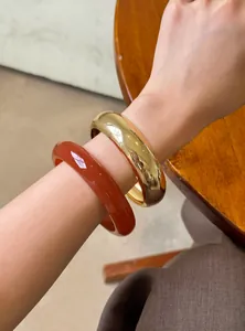 Detalle de un brazalete dorado vintage y una pulsera de resina acrílica marrón rojizo