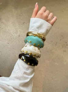 Detalle de brazaletes vintage apilados de acrílico y tono dorado con tachuelas doradas