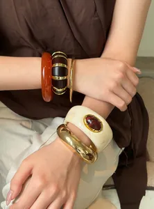 Vista detallada de pulseras vintage de acrílico y metal dorado en la muñeca mujer