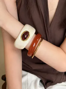 Primer plano de pulseras vintage de acrílico en ámbar y crema en un brazo