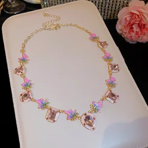 Detailansicht der Emaille-Schmetterlingshalskette mit rosa Edelsteinen auf weißem Display