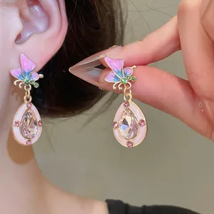 Nahaufnahme eleganter Schmetterlings-Ohrhänger mit rosa Kristallen und Emaille-Finish.