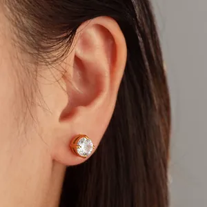 Vue détaillée d'une boucle d'oreille puce en zircone ronde avec monture dorée à griffes.
