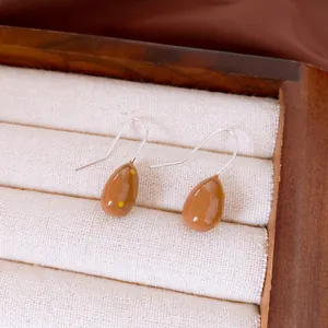 Dettaglio orecchini a goccia marroni a pois gialli con eleganti ganci in argento lucido