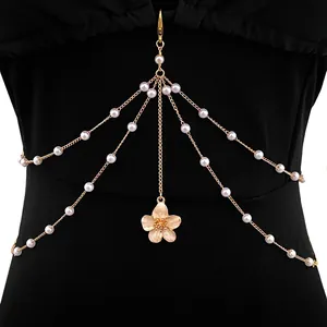 Detail of a multi-layer body chain featuring pearls and a delicate pink flower pendant
