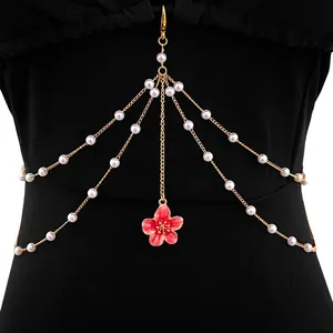 Detailed close-up view of elegant gold body chain with white pearls and red flower