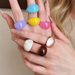 Colorful marbled geometric resin rings worn on a hand