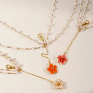 Detail view of colorful cherry blossom pendants on elegant gold pearl layered body chains