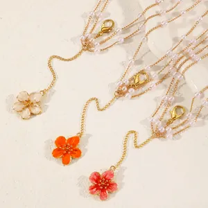 Close-up of multi-layer pearl body chains with orange, red, and cream flower pendants