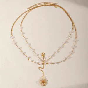 Macro view of multi-layered gold body chain with pearls and flower pendant detail