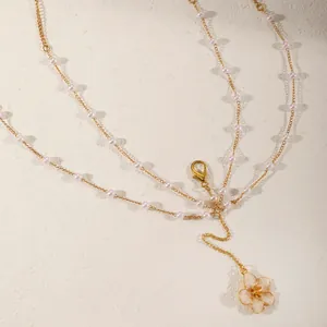 Elegant gold body chain featuring white pearls and a delicate cherry blossom flower pendant.