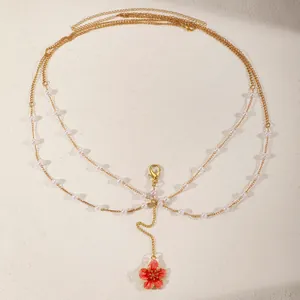 Detailed view of gold multi-layer body chain with pearls and pink flower pendant