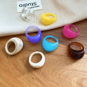 Detailed view of colorful chunky geometric resin rings displayed on a wooden surface.