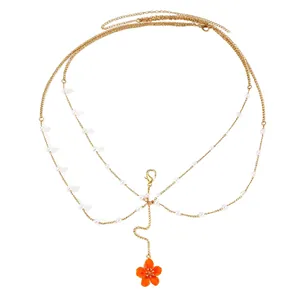 Detailed view of elegant multi-layered gold body chain featuring orange flower and pearls